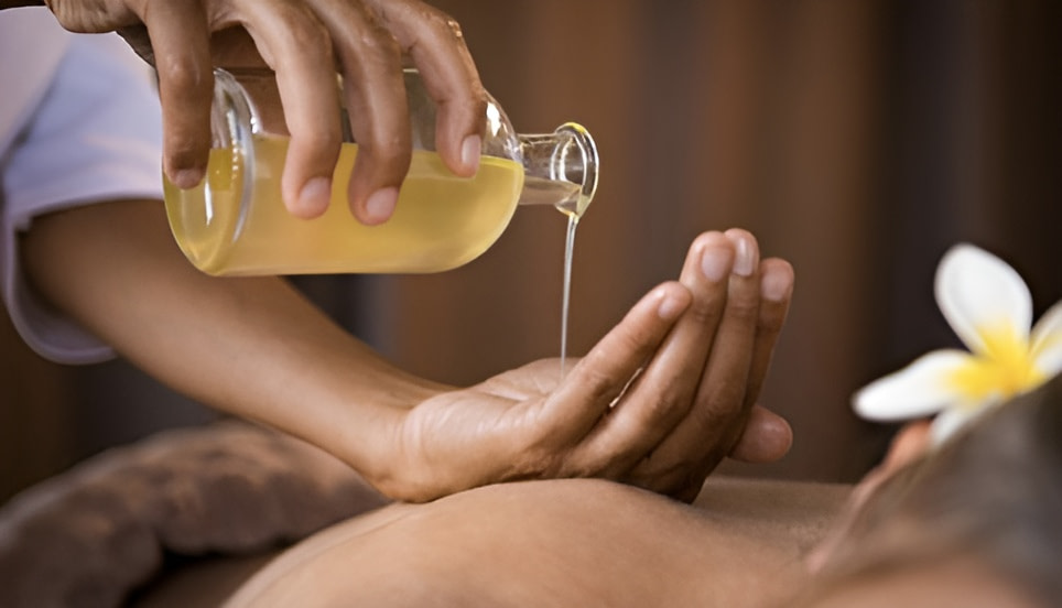 Massage aromathérapie avec de l'huile qui coule dans la main d'une masseuse. La main est posée sur la personne massée.